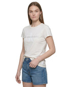 Woman wearing a Calvin Klein white t-shirt and denim shorts on a white background