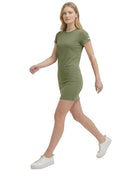 Woman wearing a green Calvin Klein dress and white sneakers on a white background