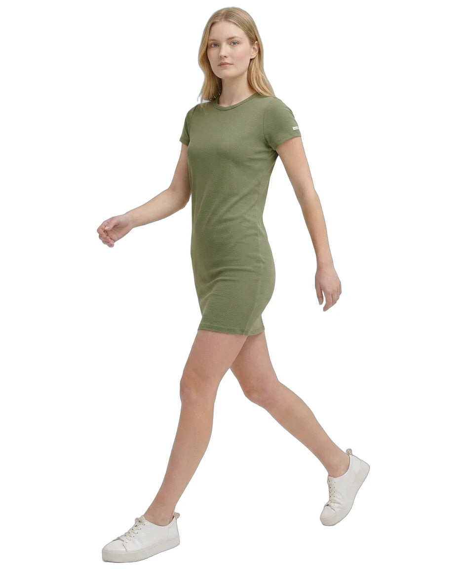 Woman wearing a green Calvin Klein dress and white sneakers on a white background