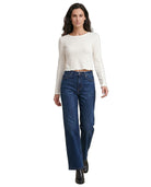 Woman wearing a white long-sleeve top and blue jeans on a white background
