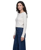 Woman wearing a white long-sleeve top and blue jeans on a white background