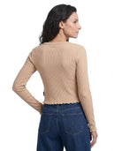 Woman wearing a beige long-sleeve top and blue jeans on a white background