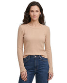 Woman wearing a beige long-sleeve top and blue jeans on a white background