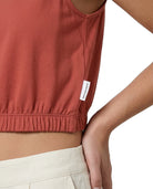 Person wearing a red sleeveless top with a brand label on a white background