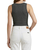 Person wearing a gray tank top and white pants on a white background