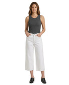 Woman wearing a gray tank top and white pants on a white background