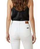 Person wearing a black top and white pants with a brown patch on a white background