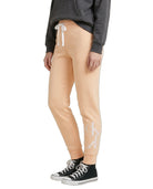 Person wearing beige jogger pants with a logo, black sneakers, and a gray sweatshirt on a white background.