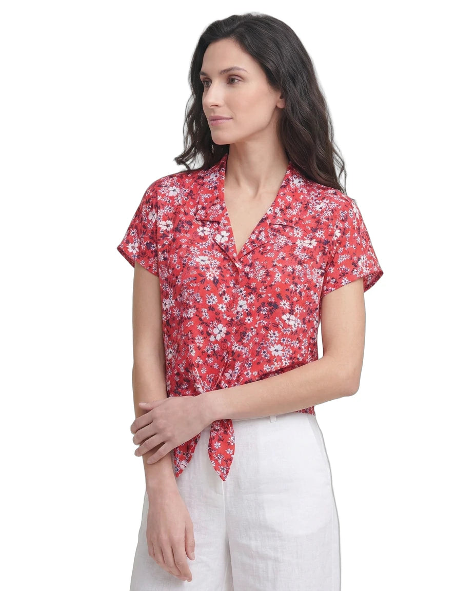 Woman wearing a red floral Calvin Klein blouse against a white background