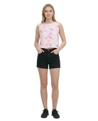 Woman wearing a pink floral sleeveless top and black shorts on a white background