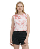 Woman wearing a sleeveless pink and white tie-dye top with black shorts on a white background
