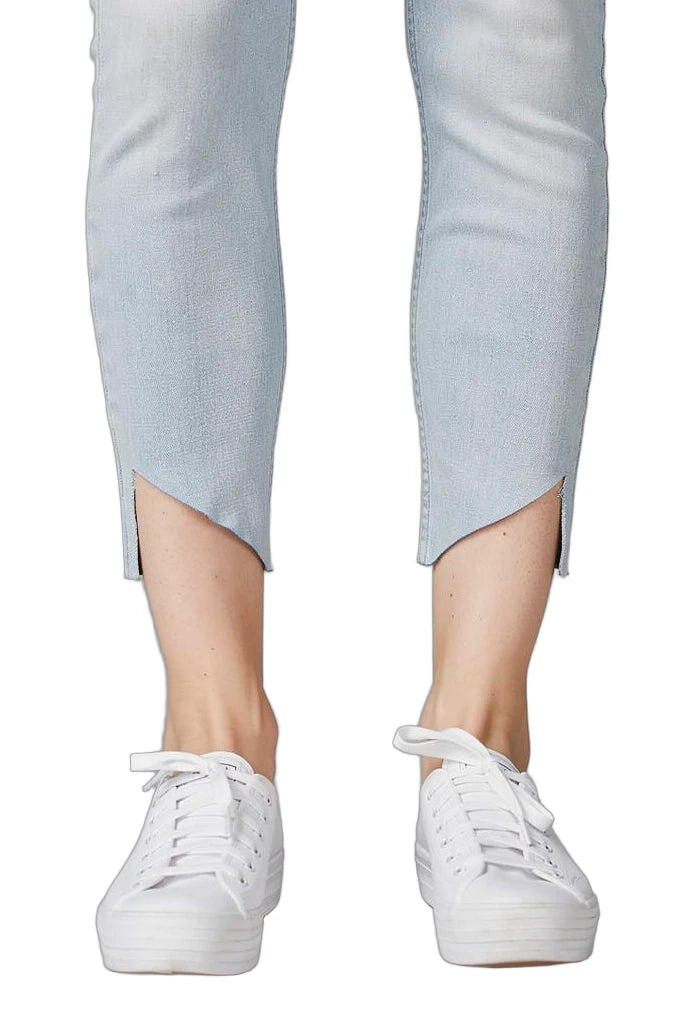 White sneakers worn with light blue pants on a white background