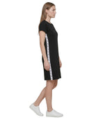 Woman wearing a Calvin Klein black dress with white tape design on a white background