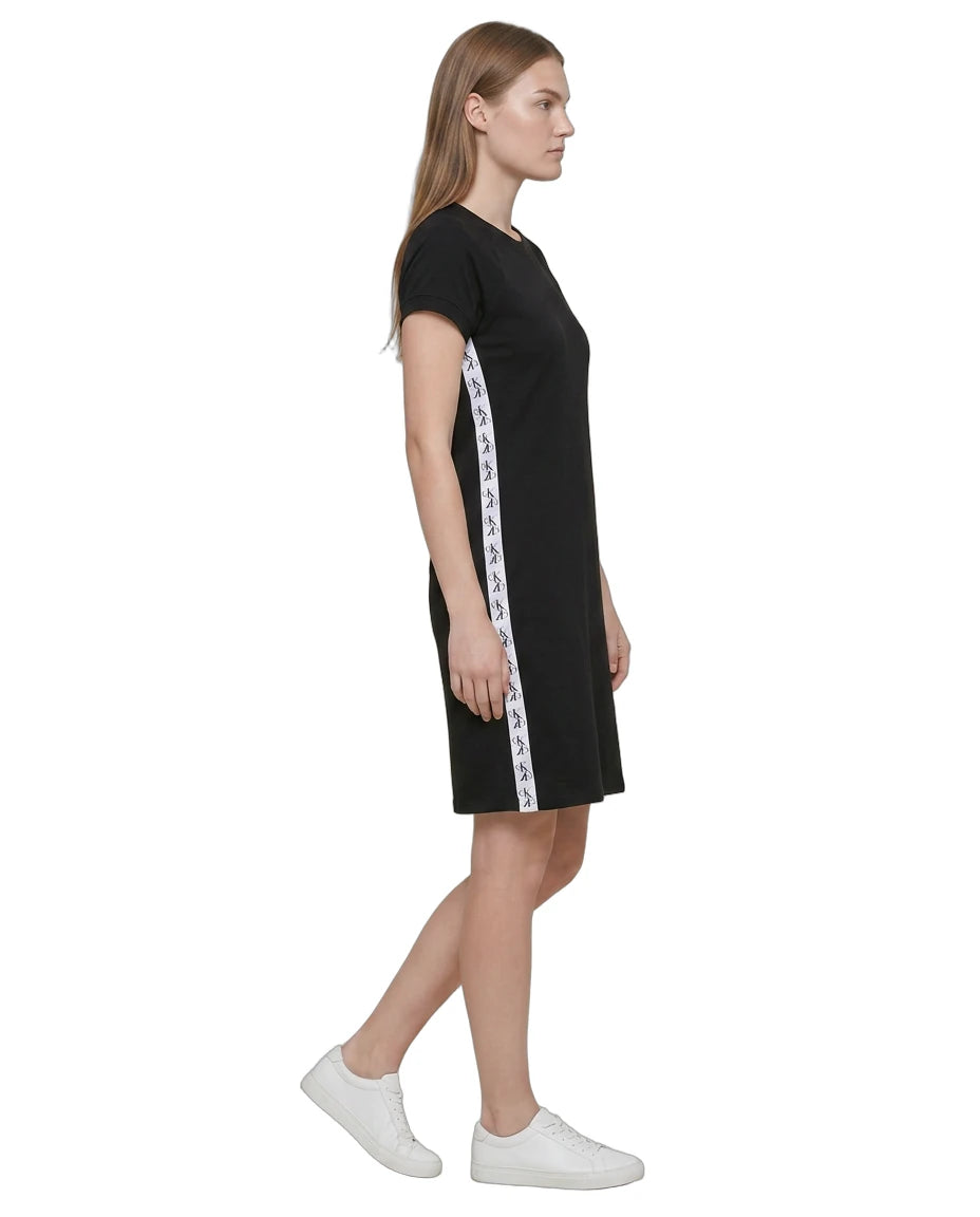 Woman wearing a Calvin Klein black dress with white tape design on a white background
