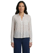 Woman wearing a light patterned Calvin Klein shirt and dark pants on a white background