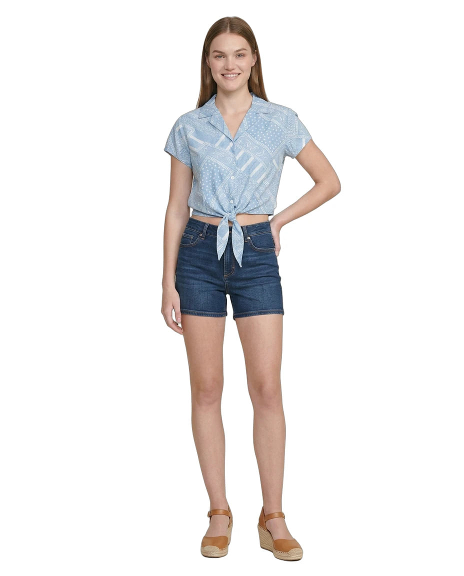 Woman wearing a blue patterned Calvin Klein top and denim shorts on a white background