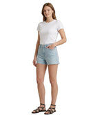 Woman wearing a white t-shirt and light blue Calvin Klein denim shorts on a white background