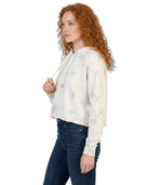 Woman wearing a white tie-dye Calvin Klein hoodie and dark jeans on a white background