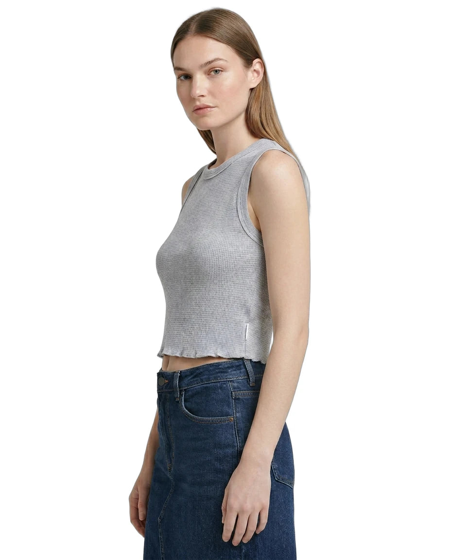 Woman wearing a gray sleeveless Calvin Klein top and blue jeans on a white background