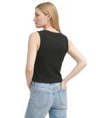 Woman wearing a black sleeveless top and light blue jeans on a white background