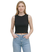 Woman wearing a black sleeveless top and blue jeans on a white background