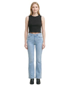 Woman wearing a black sleeveless top and light blue jeans on a white background