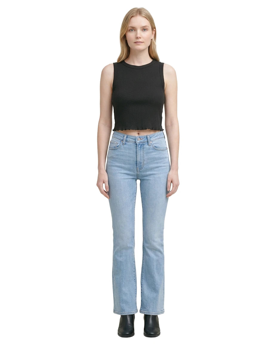 Woman wearing a black sleeveless top and light blue jeans on a white background