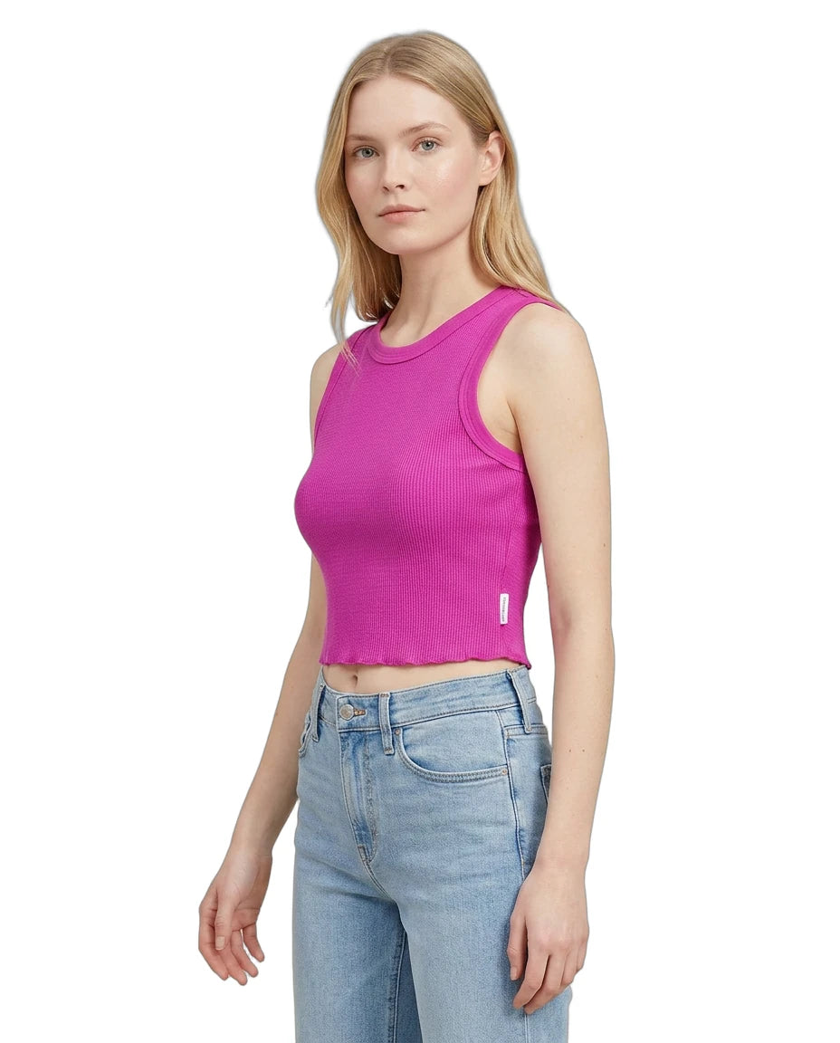 Woman wearing a bright pink tank top and light blue jeans on a white background