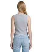 Person wearing a light gray sleeveless top and light blue jeans on a white background