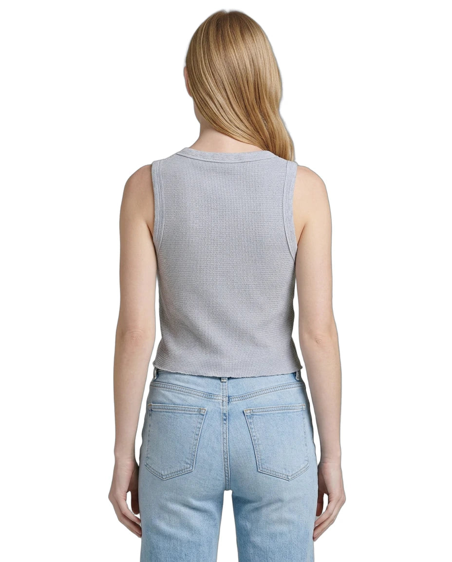 Person wearing a light gray sleeveless top and light blue jeans on a white background