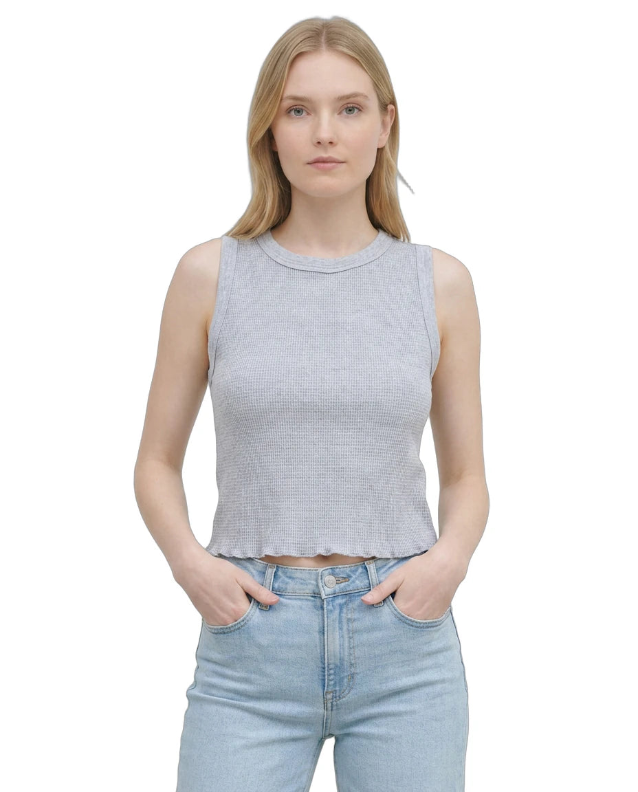 Woman wearing a sleeveless gray top and light blue jeans on a white background