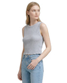 Woman wearing a gray sleeveless top and light blue jeans on a white background
