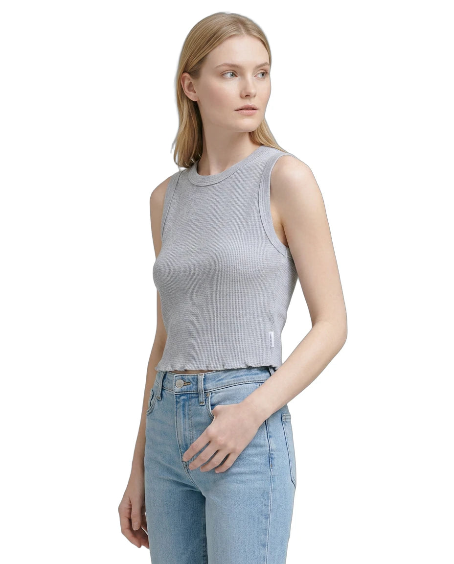 Woman wearing a gray sleeveless top and light blue jeans on a white background