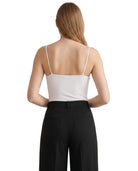 Person wearing a white Calvin Klein bodysuit and black pants on a white background