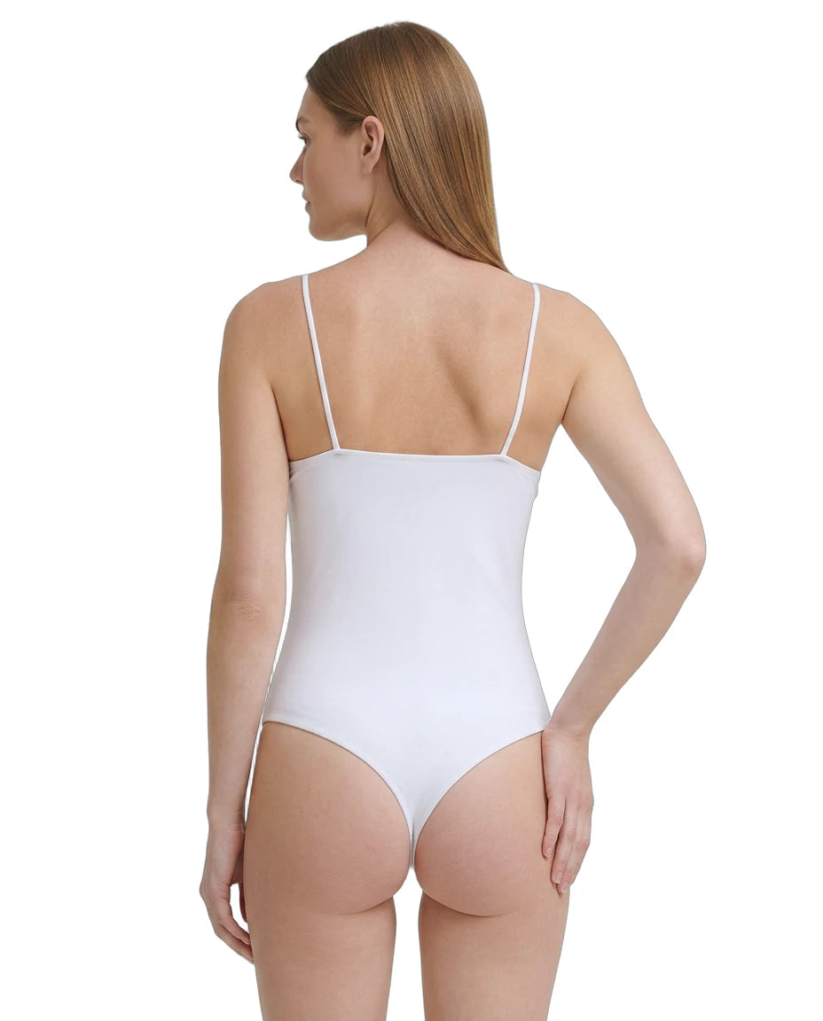 Woman wearing a white Calvin Klein bodysuit with thin straps on a plain background