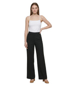 Woman wearing a white Calvin Klein bodysuit and black wide-leg pants on a white background