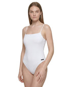 Woman wearing a white Calvin Klein bodysuit on a white background