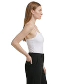 Woman wearing a white Calvin Klein bodysuit and black pants on a white background