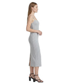 Woman wearing a gray Calvin Klein dress with a side slit on a white background