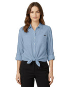 Woman wearing a blue Calvin Klein button-up shirt with a brand logo on a white background