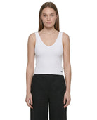 Woman wearing a white Calvin Klein tank top and black pants on a white background