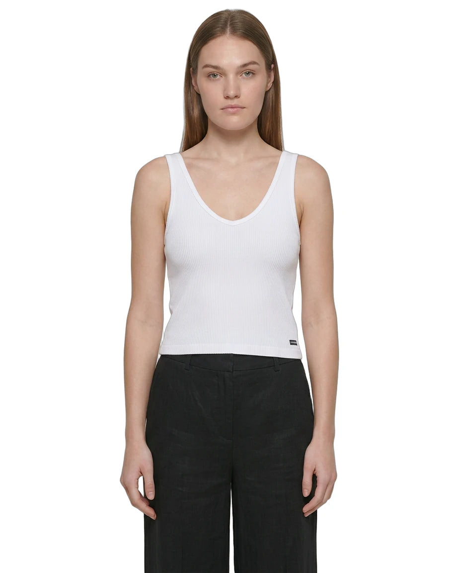 Woman wearing a white Calvin Klein tank top and black pants on a white background