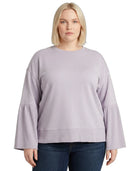 Woman wearing a light purple Calvin Klein sweater with ruffled sleeves on a white background