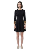 Black Calvin Klein dress with leopard print cuffs worn by a model on a white background