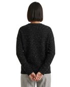 Person wearing a black speckled sweater on a white background