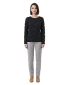 Woman wearing a black sweater with gold buttons and gray pants on a white background