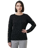 Woman wearing a black speckled sweater with gold buttons on a white background