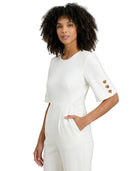 Woman wearing a white outfit with gold buttons on a white background