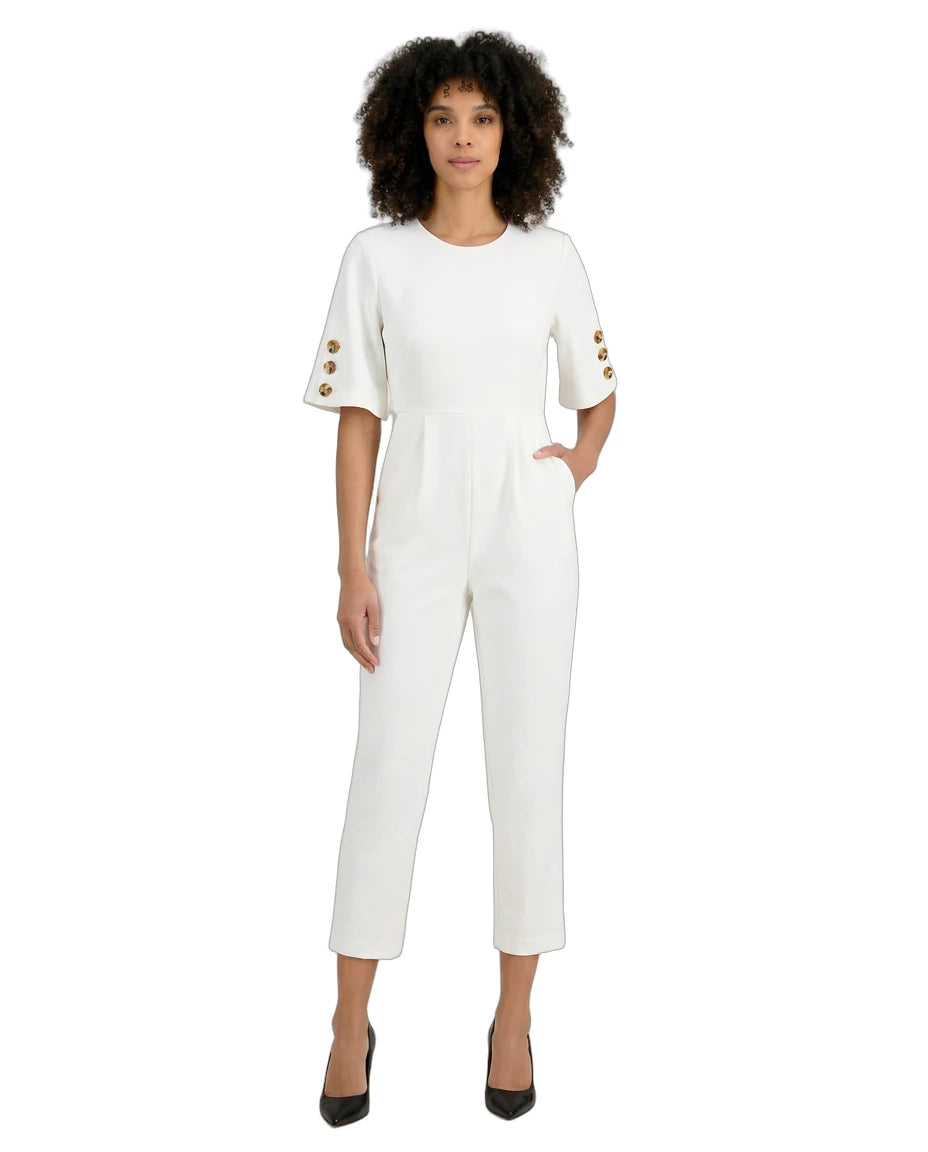 Woman wearing a white jumpsuit with gold buttons on a white background