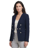 Woman wearing a navy blazer with white buttons on a white background